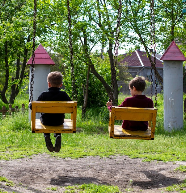 Фото Два веселых мальчика катаются на качелях