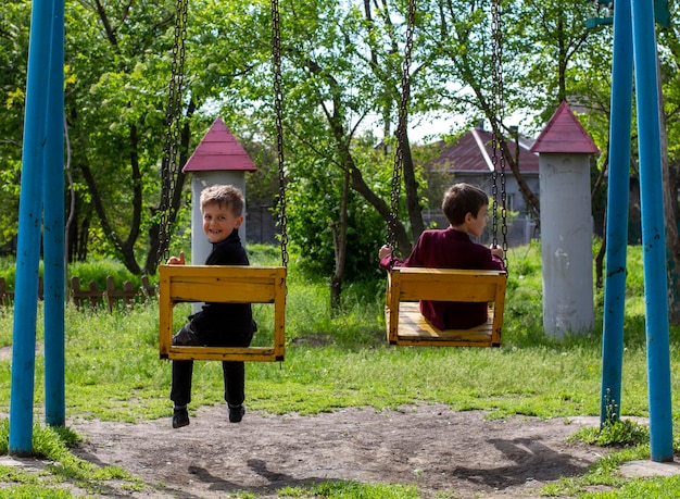 Фото Два веселых мальчика катаются на качелях