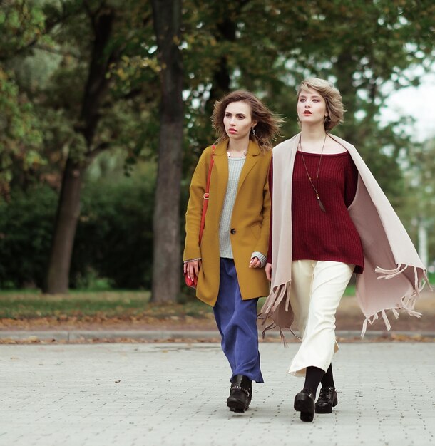 Two cheerful fashion girls in the autumn park