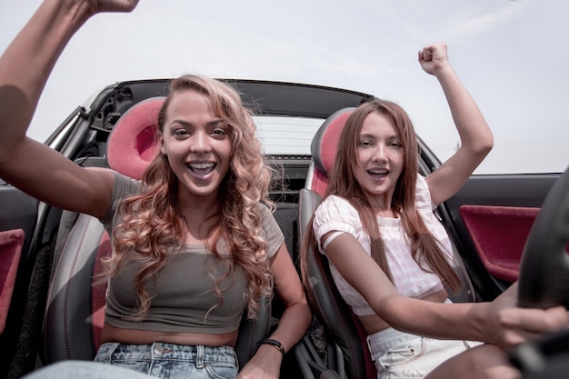 Two cheerful girlfriends on a walk in a convertible