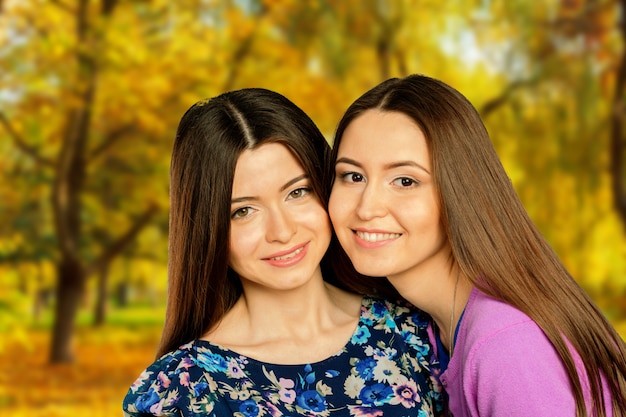 Two cheerful girls twins, in the street autumn park