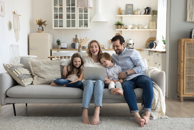 Photo two cheerful little kids happy mom and dad enjoying leisure at home together using laptop on sofa talking on video call laughing watching movie interactive online tv channel