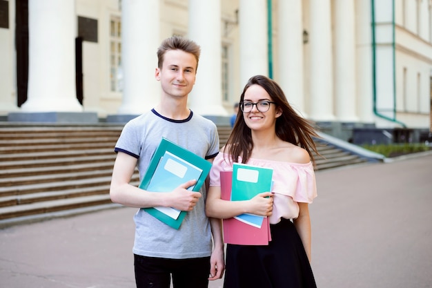 Due allegri studenti, tenendo quaderni e cartelle.