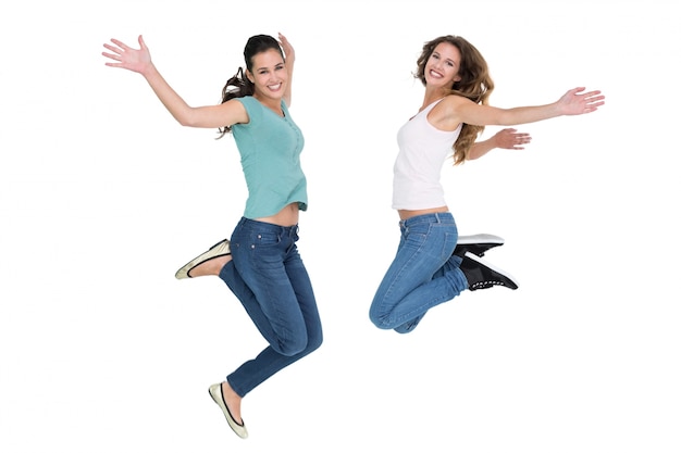 Two cheerful young female friends jumping