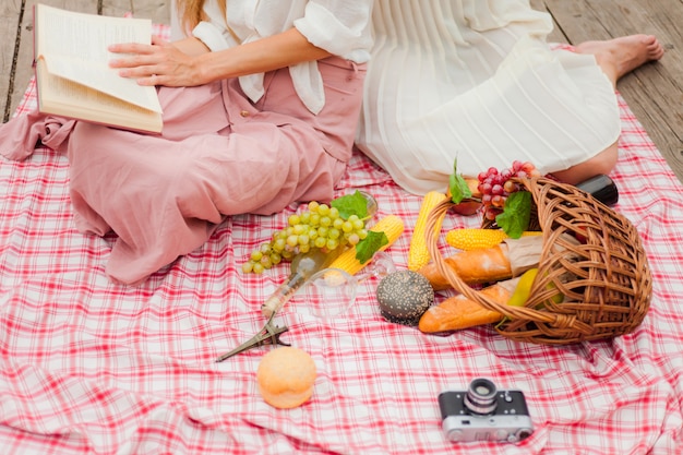 2人の陽気な若い女性は、夏の日に屋外でピクニックをします。