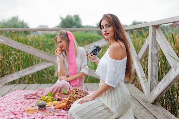 Две веселые молодые женщины пикник на улице в летний день.