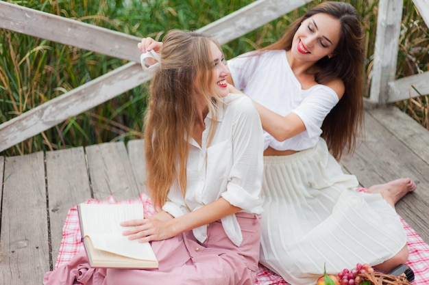 Two cheerful young women have a picnic outdoors on a summer day.