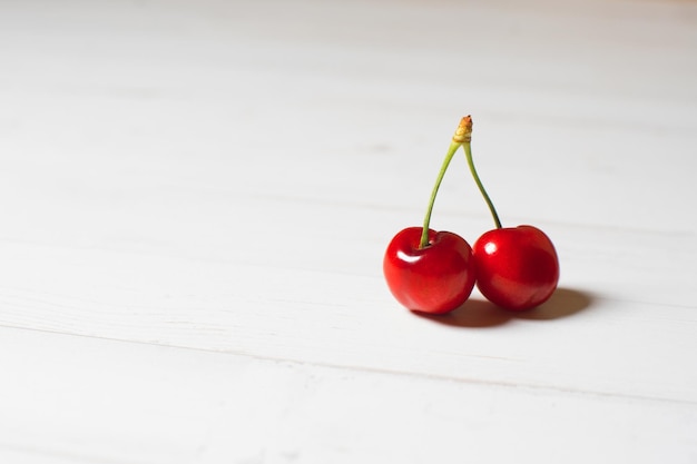 Two cherries on a white table