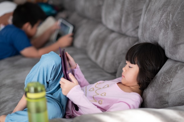Two children addicted tablet, asian kid watching cartoon