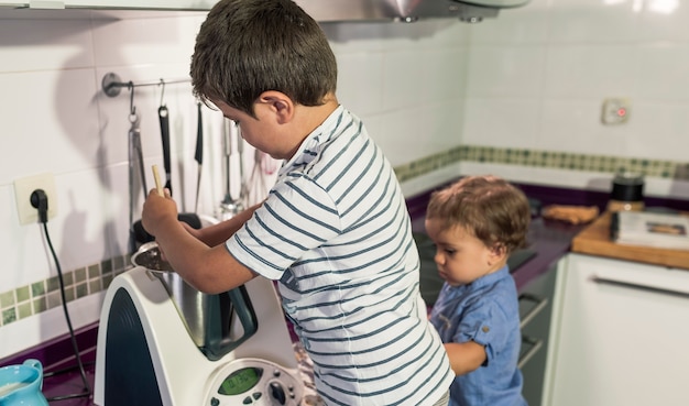 Due bambini che cuociono la torta a casa.