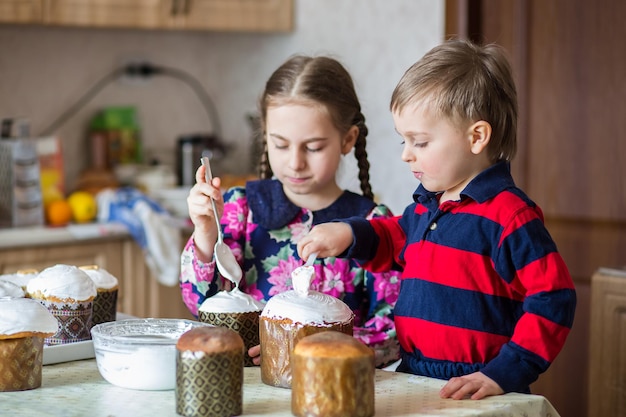 Two children a girl and a boy a brother and sister icing an Easter cake