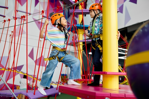 Two children in helmets climb on zip line