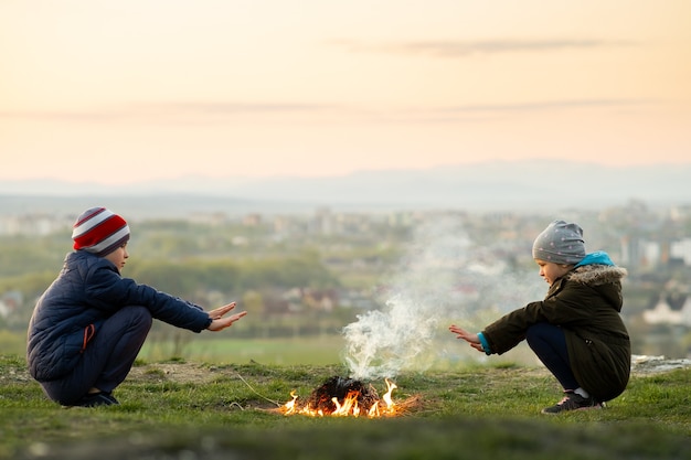 Due bambini che giocano con il fuoco all'aperto quando fa freddo