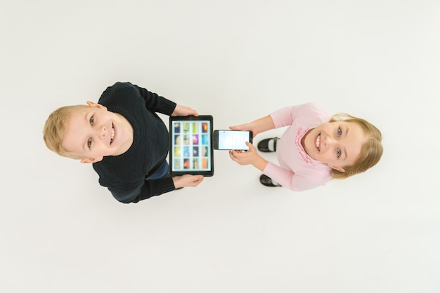 2人の子供はデバイスを持って立っています。上から見る