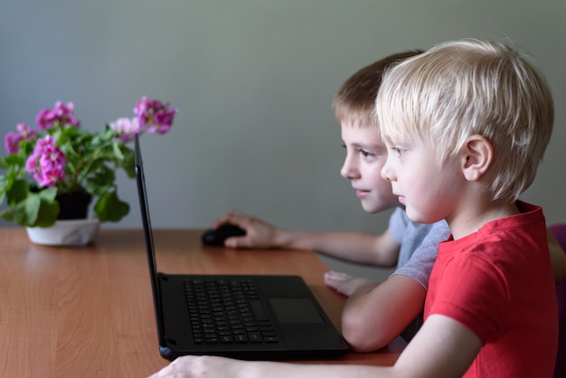 Two children use a laptop