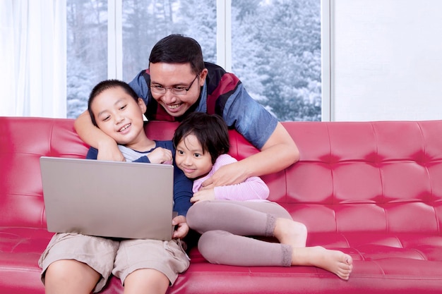 Two children watch a movie with their father