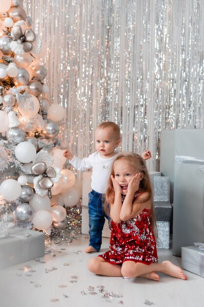 two children with gifts near the Christmas tree photo zone