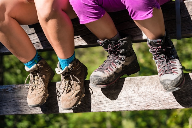 Two children with hiking boots sitting on rail of bridge 