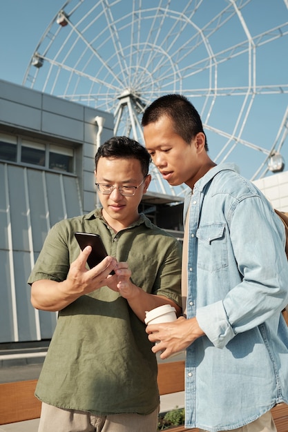 スマートフォンの画面を見ているカジュアルウェアの2人の中国人ビジネスマン