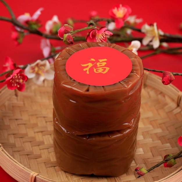 Два китайских новогодних торта (китайский иероглиф «фу» означает удачу). популярный как куэ керанжанг или додол китай в индонезии. подается на бамбуковой тарелке, украшение из цветов имлек