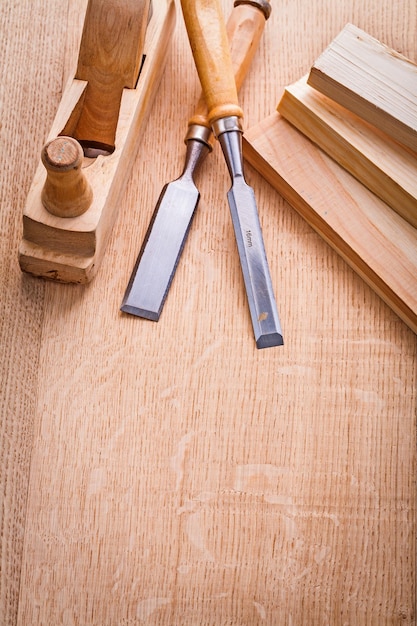 Two chisels woodworkers plane and wooden planks on board with copyspace