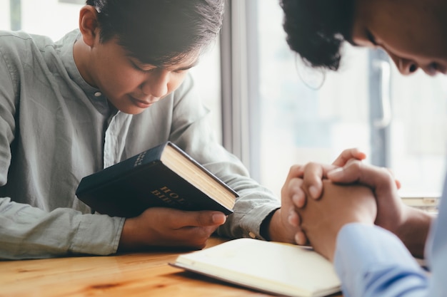 Photo two christian people are praying together over holy bible.