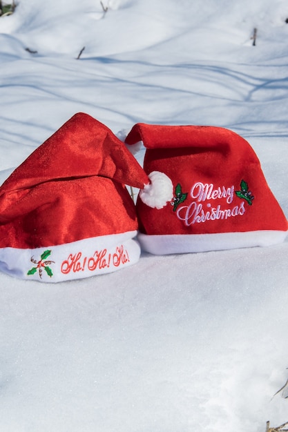 Two Christmas red hats on the white snow holiday celebration concept