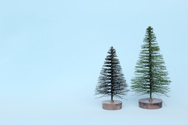 Two Christmas trees on light  background in minimal style. Christmas ornaments, new year and winter concept.