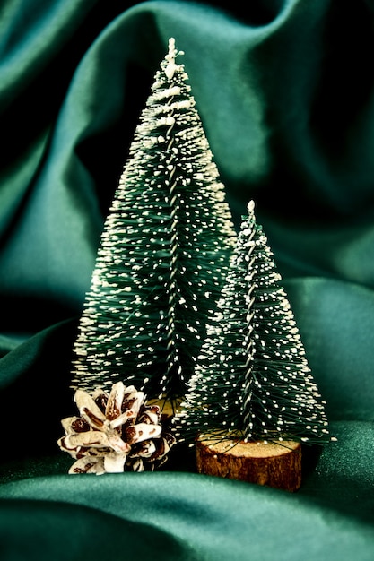 Фото Две рождественские елки на зеленом шелковом фоне. модное украшение. празднование рождественских каникул. новогодняя концепция. открытка. новогодний фон с елкой. копировать пространство
