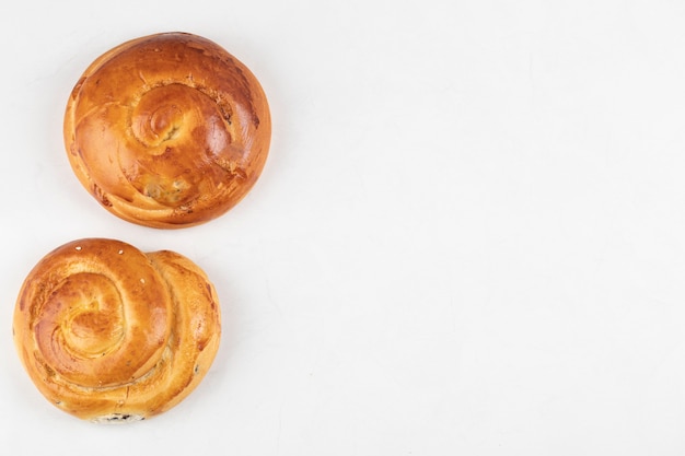 Two circle shaped fresh pastries on a white surface 