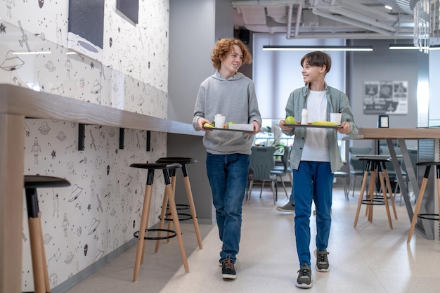 Foto due compagni di classe passeggiano tra i tavoli della mensa scolastica