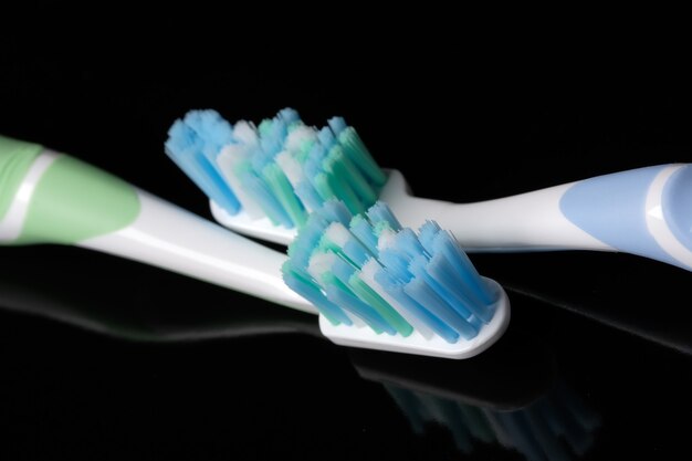 Two clean new toothbrushes on a black mirror background close-up macro photography