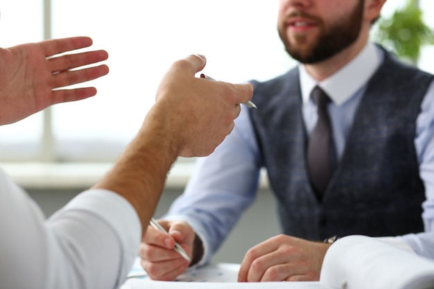 Two clerk businessmen with silver pen in arms deliberate on problem