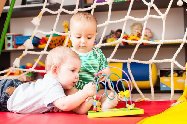 Two clever boys babies playing with toy in playroom