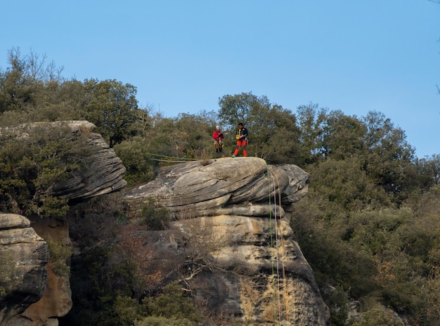 Two climbers preparing to rappel down a gorge with ropes at the ready