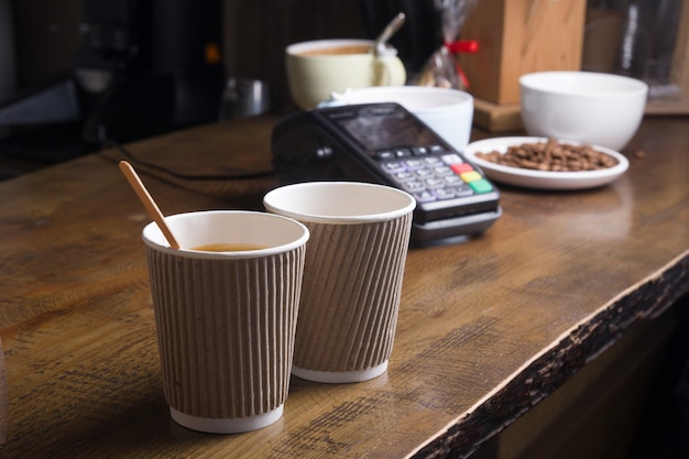 Foto due caffè in un bicchiere artigianale e un terminale di pagamento