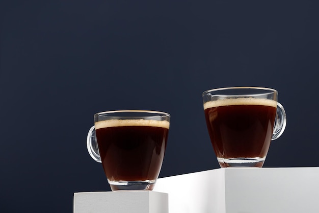 Two coffee cups with espresso in morning on white podiums and blue background Arabica Copy space