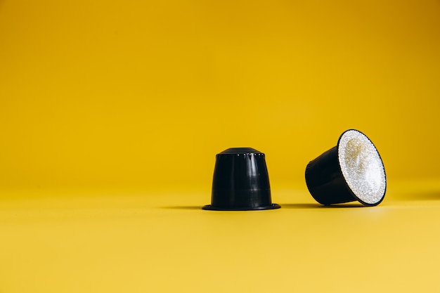 Foto due cialde di caffè con gusto aromatico sdraiate su sfondo giallo. capsule di caffè di alta qualità. primo piano, copia dello spazio.