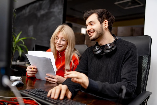 Due colleghi stanno discutendo problemi in un ufficio moderno. i colleghi uomo e donna sono seduti a tavola con il computer. piano aziendale