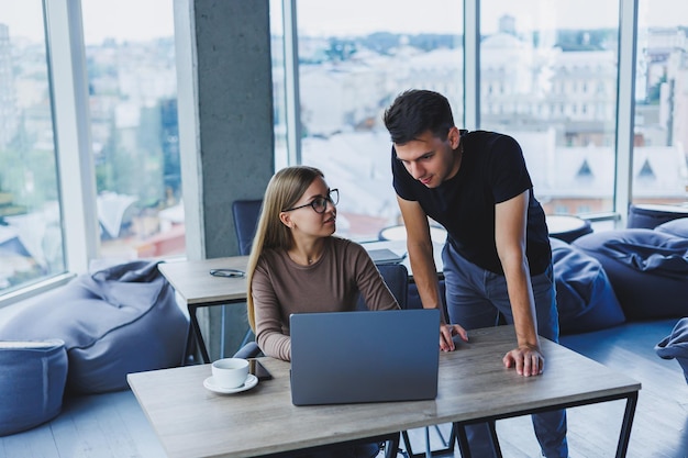 Two colleagues are discussing work on a laptop Friendly relations in the office between colleagues Workflow in the office