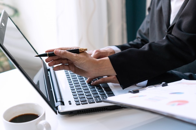 Foto due colleghi che discutono di dati con il computer portatile del computer sulla tavola dello scrittorio nell'ufficio. chiuda sull'analisi del gruppo di affari e sul concetto di strategia.