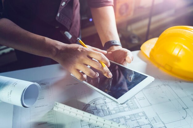 Two colleagues discussing data working and tablet laptop with on on architectural project at construction site at desk in office