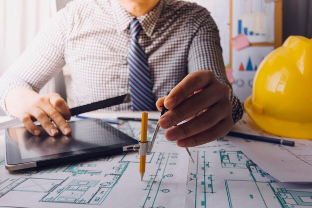 Two colleagues discussing data working and tablet laptop with on on architectural project at construction site at desk in office