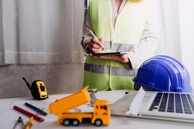 Two colleagues discussing data working and tablet laptop with\
on on architectural project at construction site at desk in\
office