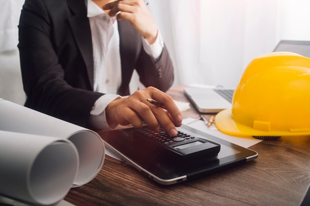 Two colleagues discussing data working and tablet laptop with on on architectural project at construction site at desk in office