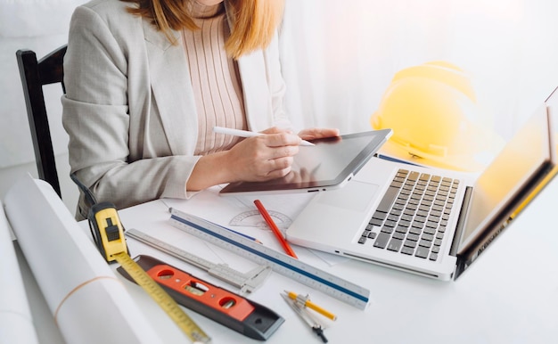 Two colleagues discussing data working and tablet laptop with\
on on architectural project at construction site at desk in\
office