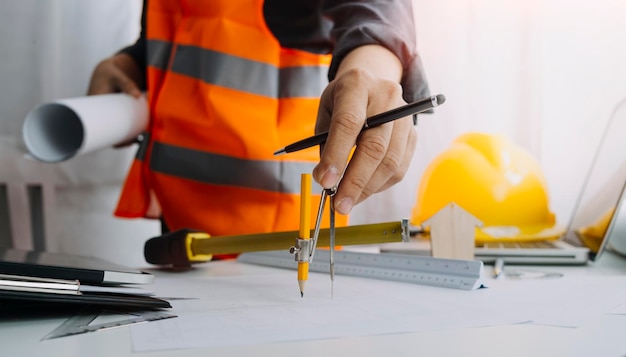 Two colleagues discussing data working and tablet laptop with\
on on architectural project at construction site at desk in\
office