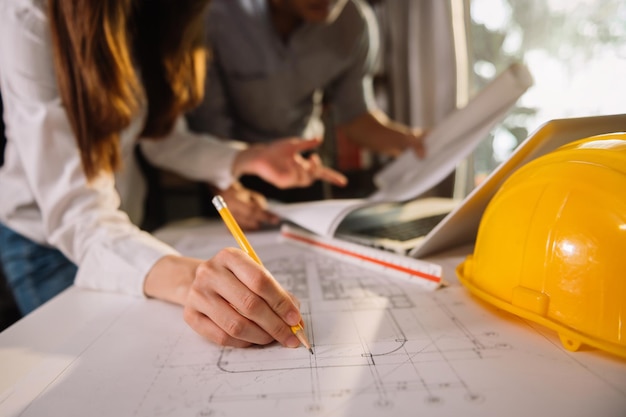 Two colleagues discussing data working and tablet laptop with on on architectural project at construction site at desk in officexA