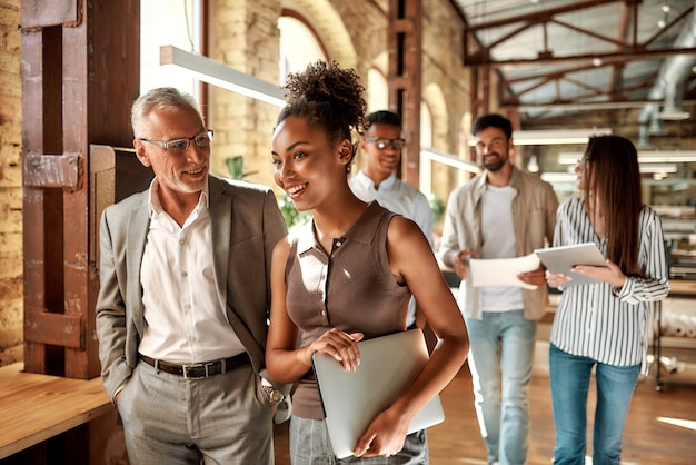 Due colleghi che discutono di qualcosa e sorridono mentre camminano nel corridoio dell'ufficio