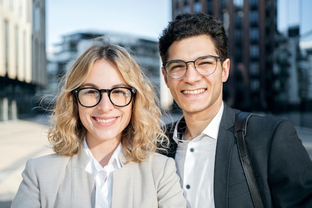 Two colleagues a woman and a man persons in business suits a close portrait smile and show